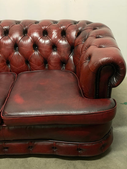Chesterfield sofa shaped on the front in burgundy leather. England, 1960s